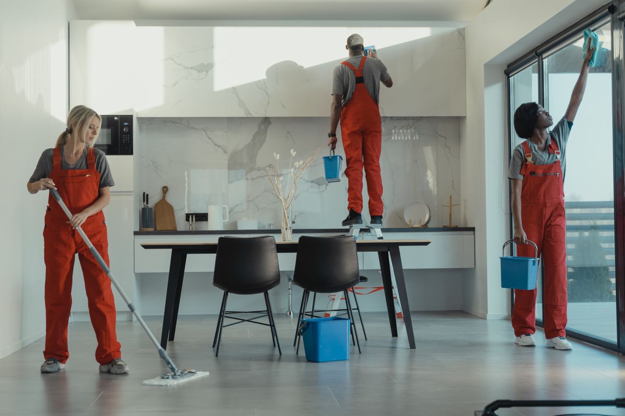 why-choose-us Group of cleaners in red uniforms mopping and wiping glass in a modern dining room.